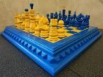 An original chess set in a bright blue and yellow design. The ash board and maple pieces are hand-painted