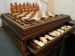 Handcrafted chess set. The board is made of ash in a dark brown color with carvings and 2 drawers for storage
