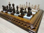 An elegant handcrafted chess set featuring a brown ombre ash board with a glossy finish and classic maple pieces