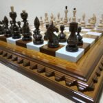 An elegant handcrafted chess set featuring a brown ombre ash board with a glossy finish and classic maple pieces
