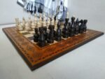 An ash chess set with fine carvings throughout the board and classic pieces in an elegant design