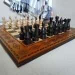 An ash chess set with fine carvings throughout the board and classic pieces in an elegant design